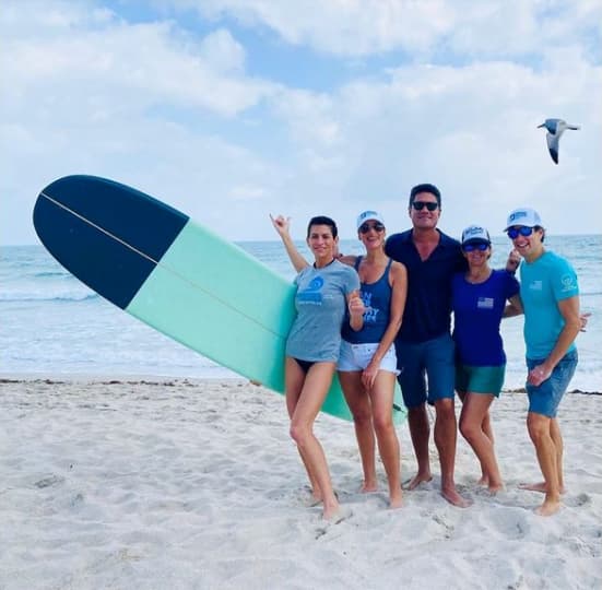 Surfrider Miami team members crowd together on a clean beach.